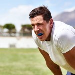 Guard your gums like you guard the ball. a young man wearing a gum guard while playing a game of rugby