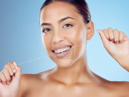 Téléchargez les photos : Floss, teeth and portrait of woman in studio for beauty, healthy body and hygiene on blue background. Female model, tooth flossing and cleaning mouth for facial smile, fresh breath and happy dental. - en image libre de droit