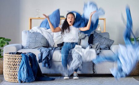 Téléchargez les photos : Laundry, frustrated and upset woman in the living room throwing the clothes with anger at her home. Crazy, busy and angry female maid, housewife or cleaner with blur motion of dirty washing at house - en image libre de droit