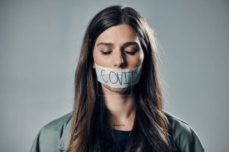 Photo for Woman, tape and mouth with silence for protest, social activism and fight against covid 19 by background. Human rights, gen z girl and studio with healthcare opinion for freedom, choice and vision. - Royalty Free Image