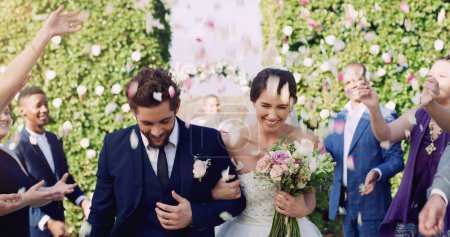 Téléchargez les photos : Happily ever afters do exist. an affectionate young newlywed couple leaving their wedding venue with their guests throwing confetti in the background - en image libre de droit