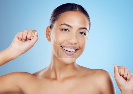 Téléchargez les photos : Floss, dental wellness and portrait of woman in studio for beauty, healthy body and hygiene on blue background. Female model, tooth flossing and cleaning mouth for facial smile, breath or happy teeth. - en image libre de droit