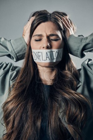 Photo for Woman, tape and mouth with quiet protest, social activism and global economy crisis by background. Inflation, gen z girl and studio backdrop with economic opinion, stress and financial freedom vision. - Royalty Free Image