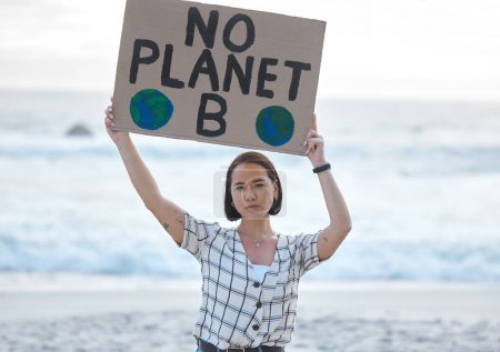 Photo for Protest, climate change and woman with a sign on the beach to stop pollution and global warming. Political, earth activism and portrait of a Asian female leader with a board by the ocean for a march - Royalty Free Image