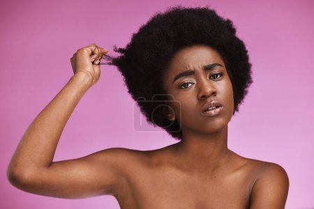 Afro hair, portrait and confused black woman in studio for grooming or treatment on purple background. Face, haircare and girl model unhappy with tangle, knot or texture after beauty routine isolated.