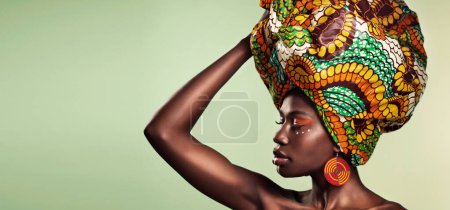 Foto de Embrace the history that brought you here. Studio shot of a beautiful young woman wearing a traditional African head wrap against a green background - Imagen libre de derechos