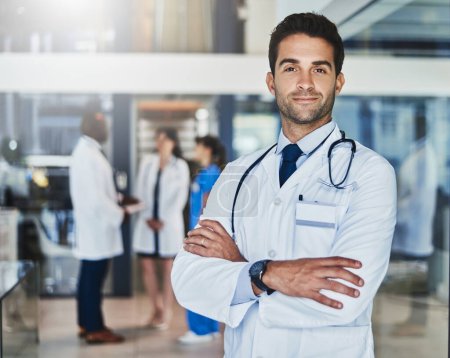 Téléchargez les photos : Your health matters most. Portrait of a confident doctor working in a hospital with his colleagues in the background - en image libre de droit
