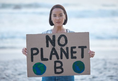 Protest, Planet Erde und Frau mit einem Zeichen für den Klimawandel, um Umweltverschmutzung und globale Erwärmung am Strand zu stoppen. Politischer, Naturaktivismus und Porträt einer asiatischen Frau mit Brett am Meer für den Marsch.