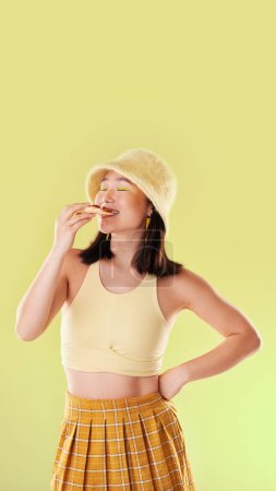 Téléchargez les photos : Pizza, lunch and eating woman with food while isolated on a yellow background in a studio. Hungry, dinner and Asian girl enjoying a snack, take away or unhealthy meal with mockup on a backdrop. - en image libre de droit