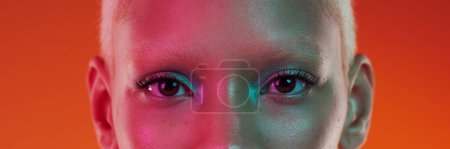 Téléchargez les photos : Maquillage, cyberpunk et portrait des yeux d'une femme isolée sur fond orange dans un studio. Edgy, créatif et bannière du visage d'un modèle tendance avec cosmétiques, glamour et fard à paupières. - en image libre de droit