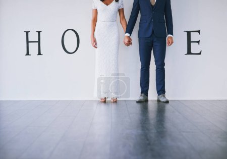 Photo for Our story starts here. Concept studio shot of a bride and groom making an M in the word home against a wall - Royalty Free Image
