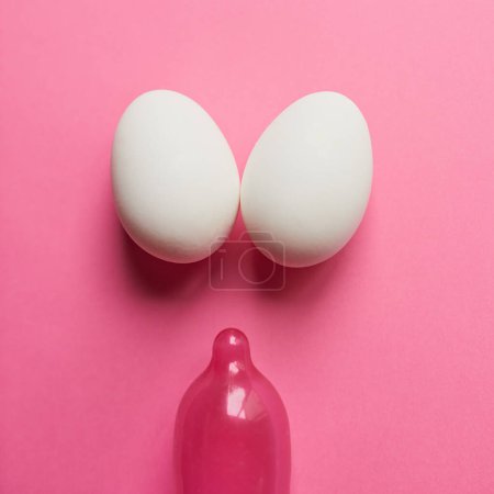 Téléchargez les photos : Double the chances but still slim. Studio shot of a pink condom and two eggs placed against a pink background - en image libre de droit