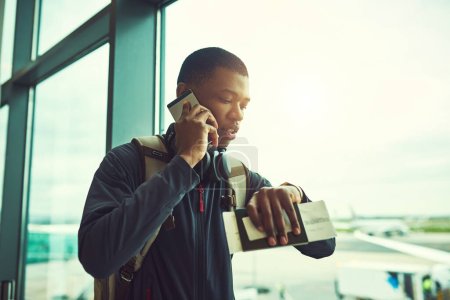 Téléchargez les photos : I hope I dont miss my flight. a young man checking the time in an airport - en image libre de droit