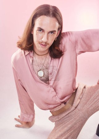 Téléchargez les photos : Portrait, vintage fashion and lgbt man from Ukraine with confidence isolated on pink background. Happy, aesthetic and male model with beauty in studio, creative non binary and gender neutral design - en image libre de droit