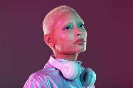 Cyberpunk fashion, black woman and headphones in studio, holographic clothes and vaporwave style. Futuristic model, young gen z and listening to music with retro aesthetic, audio technology and neon.