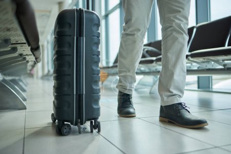 Photo for Airport, suitcase and person legs for travel, international opportunity or global journey walking in lobby. Luggage, bag and entrepreneur shoes or business man feet on vacation flight or hospitality. - Royalty Free Image
