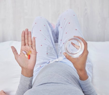 Téléchargez les photos : Pills, water and woman hands for pregnancy health, growth and wellness. Pregnant person in home bedroom above glass and Pharma medicine supplement, nutrition and iron or magnesium for development. - en image libre de droit