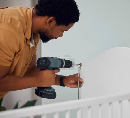 Foto de Installation, drill and man building a crib while preparing for his new baby in the family home. Engineering, metal and African father doing maintenance or repairs on the bed in nursery at his house - Imagen libre de derechos