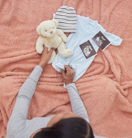 Photo for Baby clothes, scan and pregnant woman preparing for her child or infant in the nursery or bedroom. Pregnancy, love and maternal female looking at a teddy bear, outfit and xray of newborn kid at home - Royalty Free Image