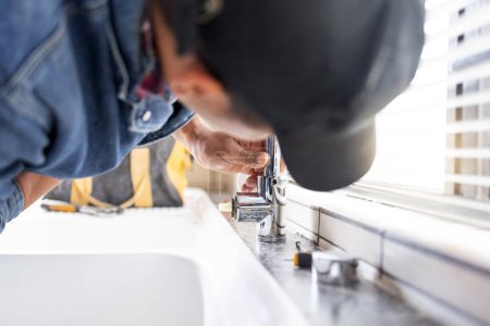 Téléchargez les photos : Plumber fixing faucet, plumbing and maintenance with man, manual labour and home renovation with trade. Construction, handyman with kitchen or bathroom sink with hardware, pipe and DIY with vocation. - en image libre de droit