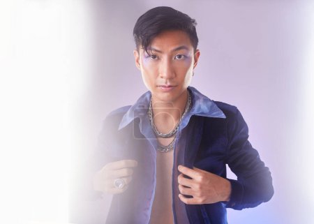 Téléchargez les photos : Makeup, light and portrait of gay man from Indonesia with confidence isolated on purple background. Style, aesthetic and lgbt fashion model with beauty in studio, non binary and gender neutral design. - en image libre de droit