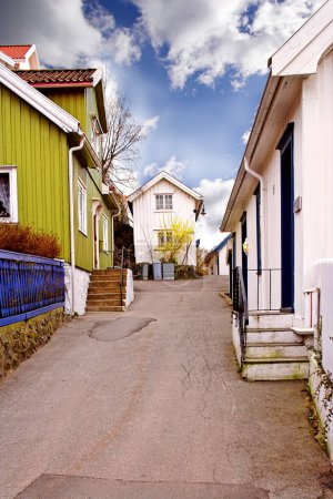 Photo for View of an empty alley or street between houses in a town or city. A narrow tar road through a small overseas village. Exploring an urban suburb as a holiday, tourism, or vacation location in Norway. - Royalty Free Image