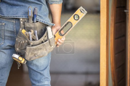 Photo for Maintenance man, bag and tools with hands, front door and home improvement service in property industry. Construction worker, back and jeans for working at house, building or real estate development. - Royalty Free Image