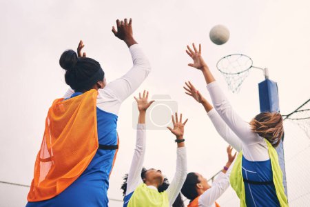 Netball, goal shooting and fitness of a girl athlete group on an outdoor sports court. Aim, sport game and match challenge of a black person with a ball doing exercise and training in a competition.