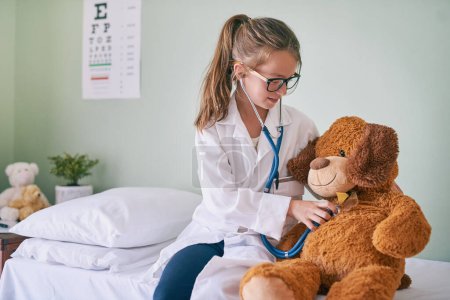 Photo for Il make sure your hugs last forever. a little girl pretending to be a doctor while examining her teddybear - Royalty Free Image