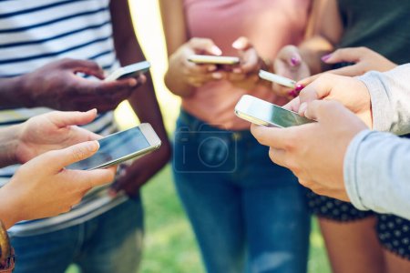 Foto de Esta generación es la mejor amiga. un grupo de amigos que usan sus teléfonos juntos al aire libre - Imagen libre de derechos