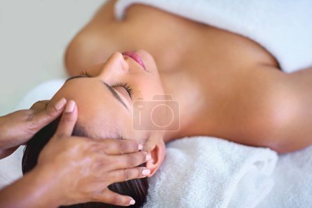 Foto de Masajeando el cuerpo y la mente. una joven recibiendo un masaje en la cabeza en un spa - Imagen libre de derechos