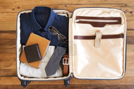 Téléchargez les photos : Plan grand angle d'une valise remplie de divers éléments essentiels pour un homme d'affaires itinérant. - en image libre de droit