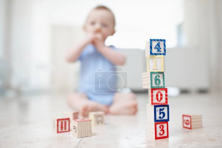 Photo for Playing with his present from Daddy. Colourful building blocks with a blurred baby in the background - Royalty Free Image