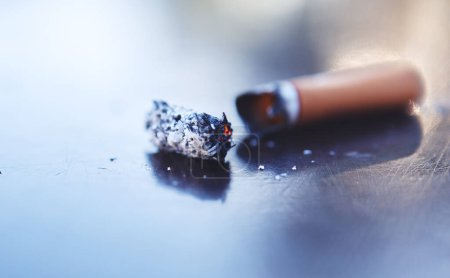 Téléchargez les photos : Smoke, ash and burning cigarette butt on table, tobacco addiction awareness and prevention of risk of lung cancer, illness and danger of death. Stop smoking for better health, lifestyle and energy - en image libre de droit