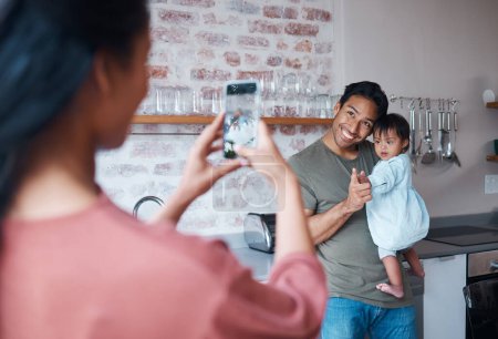 Photo for Family, care and mother with phone for photo of father and baby with down syndrome in the living room of their house. Mom taking a picture of a happy dad and child with special needs on a smartphone. - Royalty Free Image