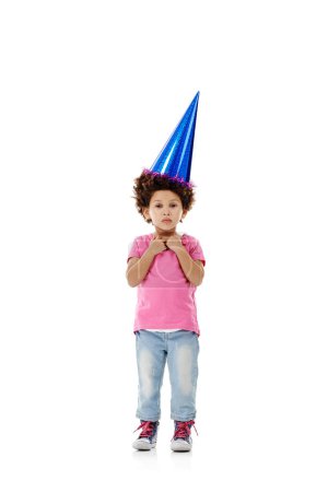 I wanted pink but they gave me blue. Studio shot of a cute little girl wearing a party hat against a white background