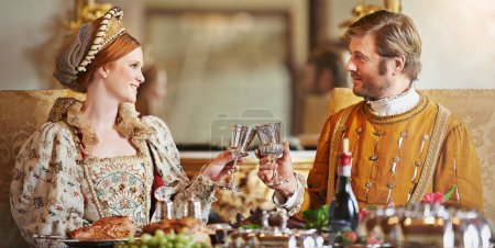 Heres to a long rule my queen. a noble couple toasting while eating together in the palace dining room