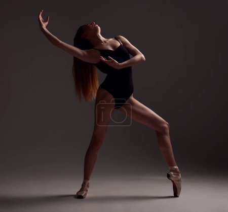 Ballet, woman and dancer with pose, exercise and training for performance on a dark studio background. Female performer, ballerina and artist with technique, practice routine for show and elegant art.
