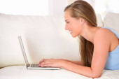 Chatting with friends online. an attractive young woman using a laptop while lying on the sofa Poster #645282558