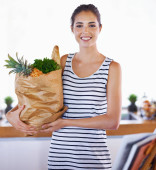 Investing in great health. An attractive woman holding a bag of groceries in the kitchen tote bag #645338964