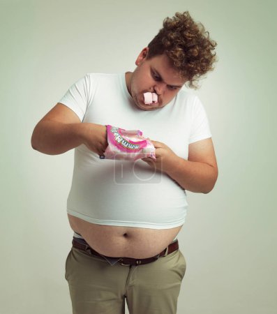Photo for Cant get enough marshmallows. an overweight man with marshmallows shoved in his mouth - Royalty Free Image