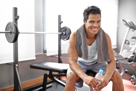 Photo for Feeling rejuvenated after that workout. A young ethnic man smiling while sitting on a weight bench at the gym - Royalty Free Image