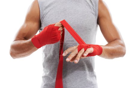 Photo for Preparing for a fight. Cropped image of a kick-boxer strapping his hands with red .hand wraps against a white background - Royalty Free Image