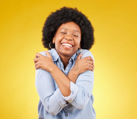 Téléchargez les photos : Femme noire, heureuse avec amour de soi et corps câlin, sourire et joie avec les yeux fermés sur fond de studio jaune. Femme est gaie, bien-être et état d'esprit positif avec l'espace de maquette, le bonheur et l'autosoin. - en image libre de droit