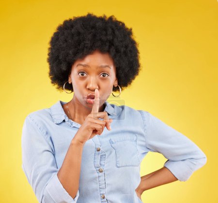 Privacy, secret and finger on lips of black woman in studio for mystery, gossip and announcement. Noise, news and whisper with female and shush gesture on yellow background for rumor, drama or silent.