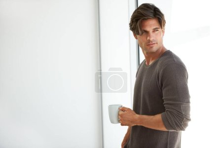 Foto de Empezar bien el día. Un joven guapo parado en casa y sosteniendo una taza de café - Imagen libre de derechos
