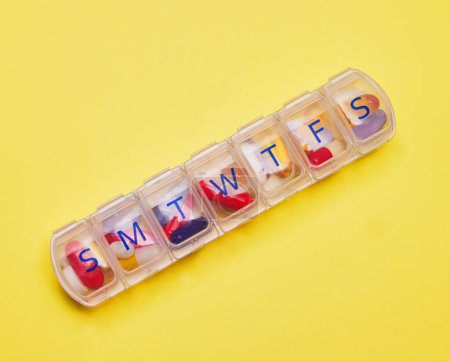 Photo for This is a reminder to take your pills. Studio shot of a pill box against a yellow background - Royalty Free Image