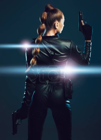 Photo for Warrior, woman and gun to fight in studio for action or danger on dark background. Strong female model, assassin or agent in scifi futuristic cosplay costume with weapon as ninja or vigilante mission. - Royalty Free Image