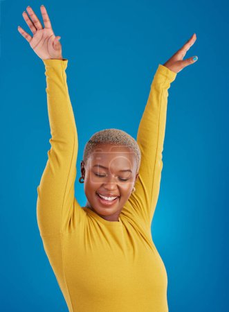 Photo for Black woman, happy and freedom celebration in studio with a smile of a winner with hands raised. African female celebrate freedom, energy dance and mindset winning prize or lottery on blue background. - Royalty Free Image