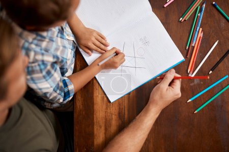 Photo for Lets sharpen our problem-solving skills. a boy playing Tic-Tac-Toe with his dad at home - Royalty Free Image